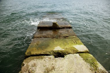Kıyı beton koruyucu yapı yok. Döşeme blokları arasında büyük derin çatlaklar shore dalga deniz etkisinin erozyon korumak. Beton takviye sahil korumaya ile büyük parçalar