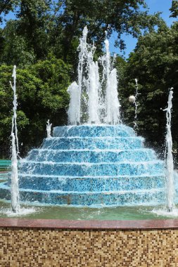 Şehir çeşme. Şehir Parkı bir sıcak yaz gününde çeşme. Su, damla ve güzel bir şehir çeşme su parlak su sıçramalarına akış. Parlak gün şehir Çeşme köpüklü su streams