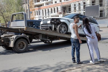 Odessa, Ukrayna - 3 Mayıs 2015: Şehir merkezinde bir araba kazası. pahalı araba çekici bir araba kazasından sonra yüklendi. Sürücü ve yolcu üzgün eser kamyonete bak.