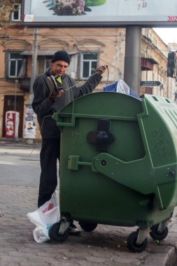 Odessa, Ukrayna - 20 Ekim 2015: çöp kutuları boş şişeler ve gıda artıkları arayan yakınındaki evsiz serseriler. Evsizler sorunu. Dilenciler - işsiz, mülteciler, göçmenler
