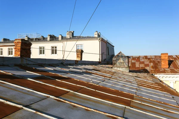 房子的旧金属屋顶是由镀锌的金属板制成的 表面有锈蚀的痕迹 城市街区锈迹斑斑的锌金属屋顶 金属腐蚀 大气对铁 锌影响的背景 — 图库照片