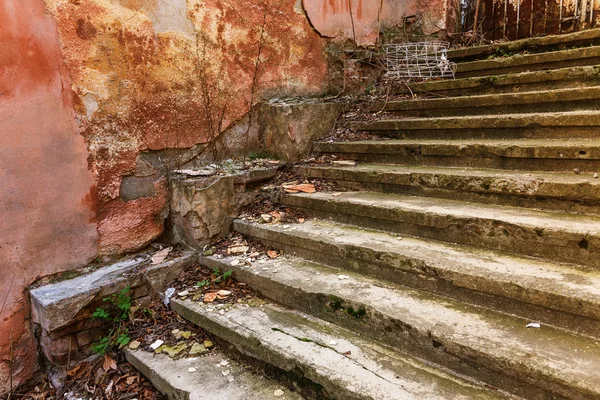 An old open outer stone staircase. Stone, cement steps of the old staircase with traces of weathering and destruction. An ancient stone staircase, ancient broken worn steps. Selective focus