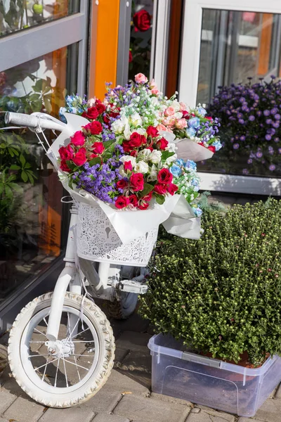 bicycle in flowers as beautiful decoration of small flower shop. Bicycle with flowers as an advertising store for sale of fresh flowers. Flower advertising installation