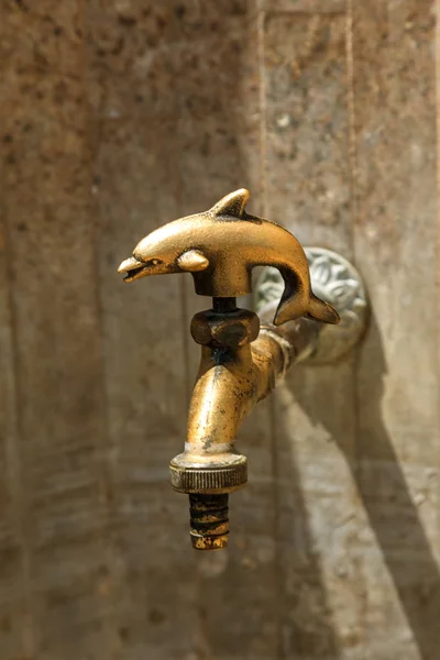 Ancient decorative tap. An old stylized vintage bronze faucet on the public street water pipe, a source of clean water for the population, Varna, Bulgaria