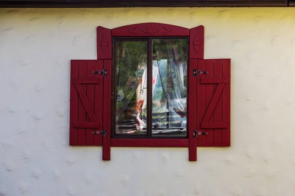 An antique painted wooden window with wooden shutters. Vintage Facade of a typical peasant house with wooden shutters