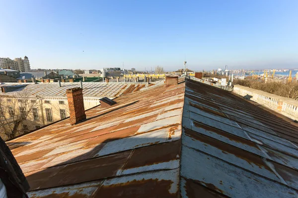 old metal roof of house is made of galvanized sheet metal with traces of surface rust. Rusty zinc metal roofs of urban quarter. Background of metal Errosion, rust, atmospheric effect on iron, zinc