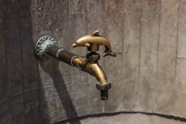 Ancient decorative tap. An old stylized vintage bronze faucet on the public street water pipe, a source of clean water for the population, Varna, Bulgaria