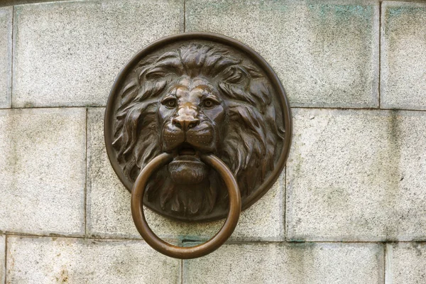 Architectural design in the form of a lion's head. Bronze lion's head with a door knocker. The image of a lion. The head of a lion.