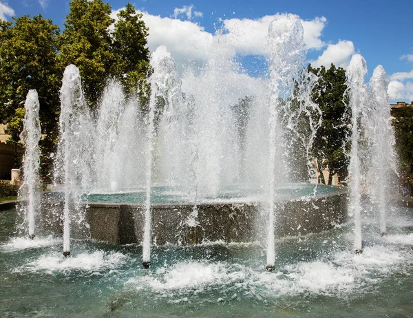 市内の噴水 夏の暑い日に公園の噴水 美しい街の噴水の水の明るい水しぶき 滴水のストリーム 市泉に輝く水の明るいストリーム — ストック写真