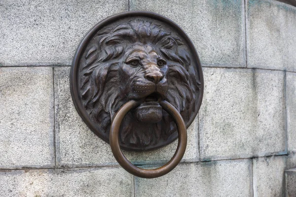 Architectural design in the form of a lion\'s head. Bronze lion\'s head with a door knocker. The image of a lion. The head of a lion.