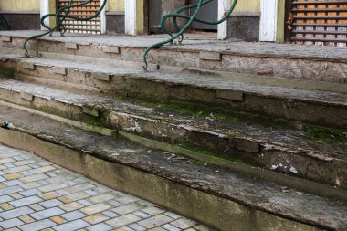 Eski, açık, taştan bir merdiven. Taş, eski merdivenlerin çimento basamaklarında yıpranma ve yıpranma izleri var. Eski taş bir merdiven, eski kırık basamaklar. Seçici odak