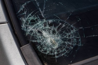 Broken car windshield. Stones on a dirty road from under the wheels at a speed smash car glass. Criminal incidents. Vandals, hooligans mutilated the car, smashed the windshield clipart