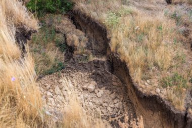 Çevreye zararlı bir bölgede dağ heyelan. Yeryüzündeki büyük çatlaklar, toprak yolu kapatan büyük katmanların inişi. Dağ yamacının yamacında baraj tehlikesi