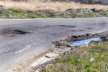 Asfalt yol ile çukurların dondurma ve çözme döngüsü sırasında belgili tanımlık kış nedeniyle zarar görmüş. Zavallı yol.