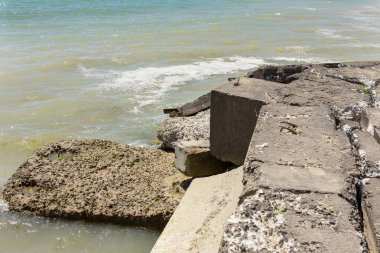Kıyı beton koruyucu yapı yok. Döşeme blokları arasında büyük derin çatlaklar shore dalga deniz etkisinin erozyon korumak. Beton takviye sahil korumaya ile büyük parçalar