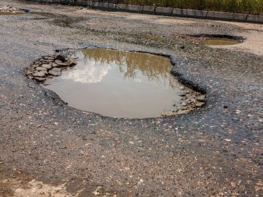 Asfalt yol ile çukurların dondurma ve çözme döngüsü sırasında belgili tanımlık kış nedeniyle zarar görmüş. Zavallı yol.