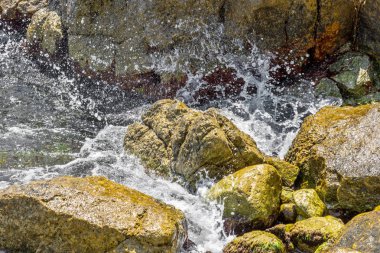 Büyük dalga sıçrama. Deniz suyu kayalar ve kayalıklarla karşı yenerek. Yukarıda ferahlatıcı güneş Zenit Beach'te mavi gökyüzü okyanus su damla.