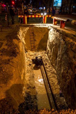 Odessa, Ukrayna - 10 Aralık 2015: inşaat işçileri Acil Onarım kentsel Karayolları geceleri mühendislik yapıyor. Onarım ve yedek su, Kanalizasyon borular alt kısmında derin bir siper gece boyunca. Kaza.