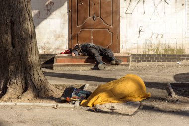 Odessa, Ukrayna - 27 Nisan 2017: Evsiz bir dilenci sokakta yatıyor. Evsiz, kirli adam asfalt sokaklarda uyurum. Sosyal sorun. Dilenciler işsiz, mülteciler, göçmenler vardır