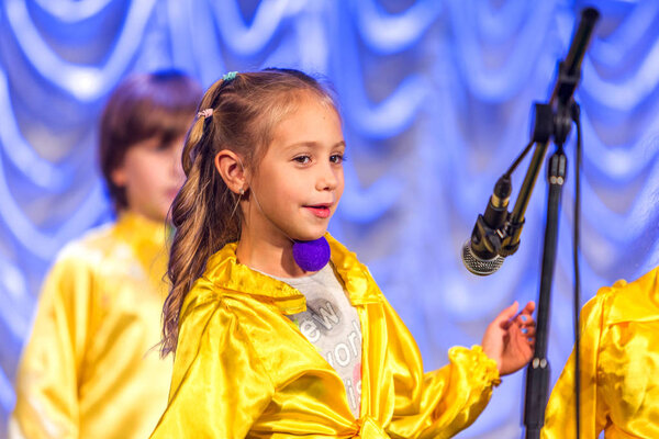 Odessa, Ukraine - December 24, 2015: Children's musical groups singing and dancing on stage in bright colorful clothes. Emotional, touching children's musical stage show.