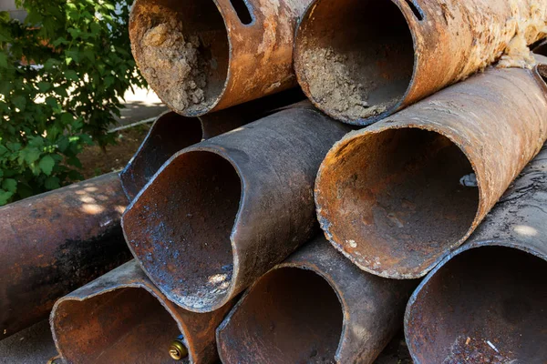Fragments of old large water pipes. After many years of operation, destroyed metal pipe was destroyed. Vegetable steel tube with hole corrosion. Rusty metal pipe. Selective focus