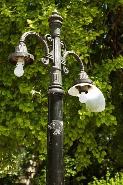 Old vintage street lamp. An antique outdoor street lamp with a broken glass plafond. Rural, inexpensive medieval street lamp