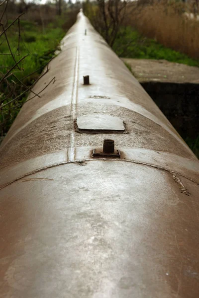 An old rusty large iron pipe of an outdated industrial waterpipe, Odessa, Ukraine, 2018. Large worn-out iron pipes for water supply of the city