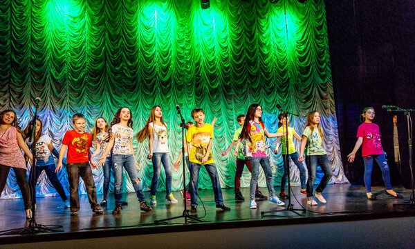 Odessa, Ukraine - December 24, 2015: Children's musical groups singing and dancing on stage in bright colorful clothes. Emotional, touching children's musical stage show.