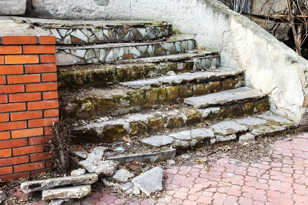 An old open outer stone staircase. Stone, cement steps of the old staircase with traces of weathering and destruction. An ancient stone staircase, ancient broken worn steps. Selective focus