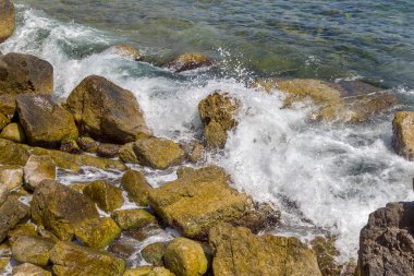 Büyük dalga sıçrama. Deniz suyu kayalar ve kayalıklarla karşı yenerek. Yukarıda ferahlatıcı güneş Zenit Beach'te mavi gökyüzü okyanus su damla.
