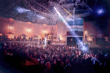 Odessa, Ukrayna - 24 Mayıs 2014: Kalabalık insan yaratıcı ışık ve müzik gösterisi sırasında bir konserde bir gece kulübünde eğleniyor. Konfeti ve büyük tiyatro kulübü parti üzerinde duman yağmuruna neşeli gençler.