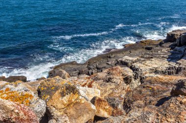 Büyük dalga sıçrama. Deniz suyu kayalar ve kayalıklarla karşı yenerek. Yukarıda ferahlatıcı güneş Zenit Beach'te mavi gökyüzü okyanus su damla.