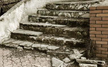 Eski, açık, taştan bir merdiven. Taş, eski merdivenlerin çimento basamaklarında yıpranma ve yıpranma izleri var. Eski taş bir merdiven, eski kırık basamaklar. Seçici odak