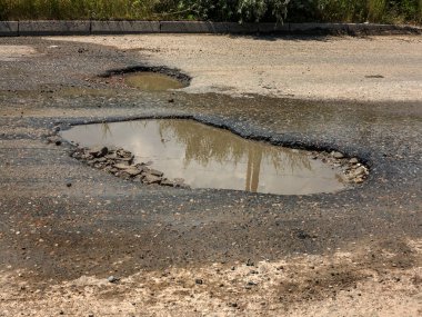 Asfalt yol ile çukurların dondurma ve çözme döngüsü sırasında belgili tanımlık kış nedeniyle zarar görmüş. Zavallı yol.