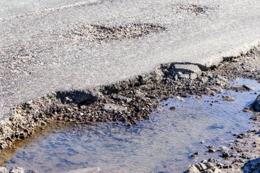 Asfalt yol ile çukurların dondurma ve çözme döngüsü sırasında belgili tanımlık kış nedeniyle zarar görmüş. Zavallı yol.