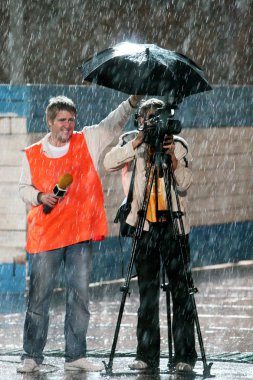 Gazeteci ve kameramanların bir futbol maçı bir şemsiye altında ağır yağmur afet ağır bir gece boyunca filme aşırı