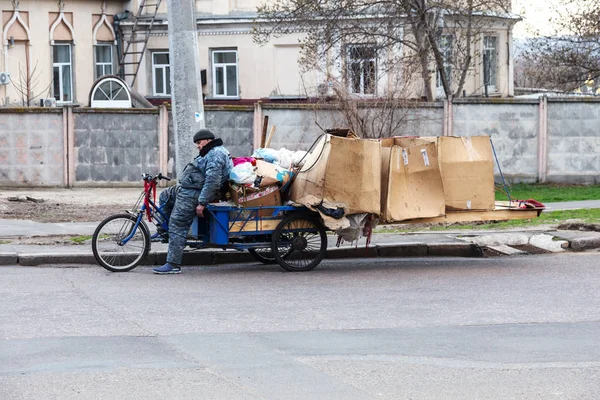 Odessa, Ukrayna - 29 Şubat 2017: Bir bisiklet üzerinde oturan evsiz biri Bagaj ile uyuyor. Evsiz bir bisiklet üzerinde yaşıyor ve yolun tam evinin karton kutu uyur