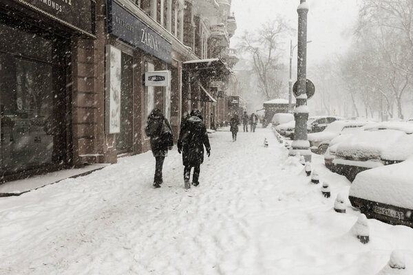 ODESSA, UKRAINE-January 16, 2018: Strong snowfall, cyclone in city streets in winter. Cars are covered with snow. Slippery road. Bad weather in winter: heavy snow and snowstorm. Pedestrians go on snow