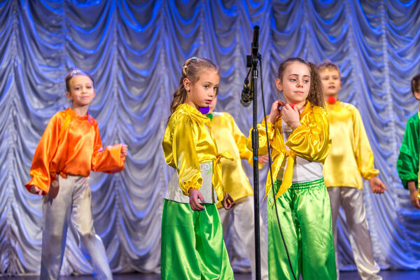 Odessa, Ukraine - December 24, 2015: Children's musical groups singing and dancing on stage in bright colorful clothes. Emotional, touching children's musical stage show.