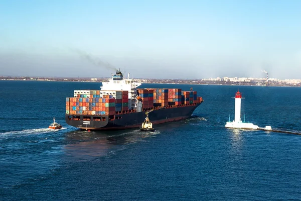 ODESSA, UKRAINE - NOVEMBER 24: Marine cargo ship loaded with shipping containers Ukrainian industrial goods coming out of harbor seaport. Vorontsov Lighthouse , November 24, 2011 Odessa, Ukraine