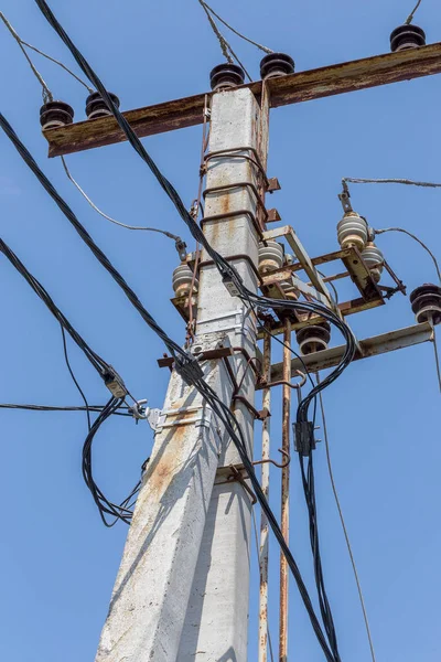 Electric pole, high-voltage electric support with wires and contact ceramic insulators against the blue sky. The concept of energy supply, electricity transit. Supply and transit of energy resources