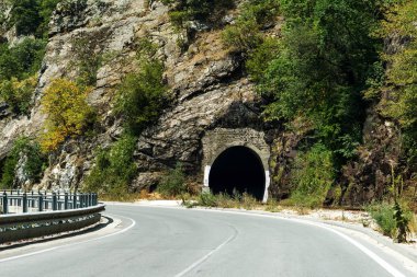 Dolambaçlı bir dağ yolu. İki yönlü yol dağlarda. Kayalık yamaçlarda taş yakınlarındaki dağlık bir alanda asfalt karayolu