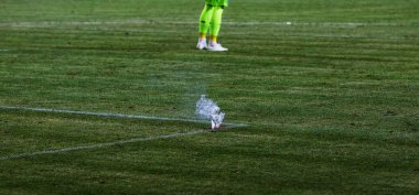 Yanan havai fişek, stadyum futbol alanının çimenlerin üzerinde bir ateş. Futbol takımı üzerinden hayran sektör standları hayranları holiganlar takım oynarken futbol sahasında yangın atmak