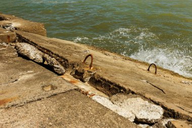 Kıyı beton koruyucu yapı yok. Döşeme blokları arasında büyük derin çatlaklar shore dalga deniz etkisinin erozyon korumak. Beton takviye sahil korumaya ile büyük parçalar