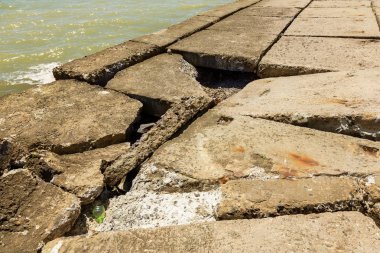 Kıyı beton koruyucu yapı yok. Döşeme blokları arasında büyük derin çatlaklar shore dalga deniz etkisinin erozyon korumak. Beton takviye sahil korumaya ile büyük parçalar