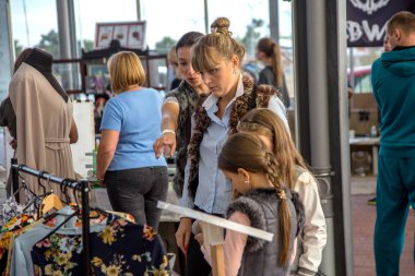 Odessa, Ukrayna - 5 Ekim 2015: Genç kadın duygusal giyimleri Fuar süresince bir göz alıcı ile moda giysiler seçmek çocuklu. Giyim Satış