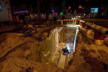 Odessa, Ukrayna - 10 Aralık 2015: inşaat işçileri Acil Onarım kentsel Karayolları geceleri mühendislik yapıyor. Onarım ve yedek su, Kanalizasyon borular alt kısmında derin bir siper gece boyunca. Kaza.