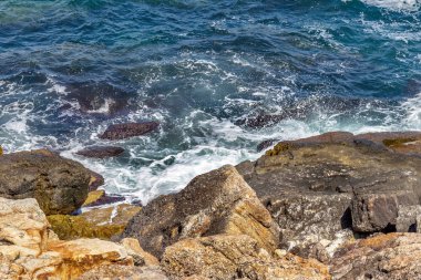 Büyük dalga sıçrama. Deniz suyu kayalar ve kayalıklarla karşı yenerek. Yukarıda ferahlatıcı güneş Zenit Beach'te mavi gökyüzü okyanus su damla.
