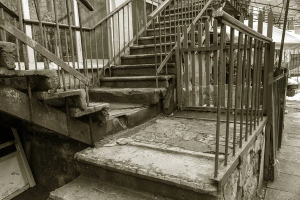 An old open outer stone staircase. Stone, cement steps of the old staircase with traces of weathering and destruction. An ancient stone staircase, ancient broken worn steps. Selective focus