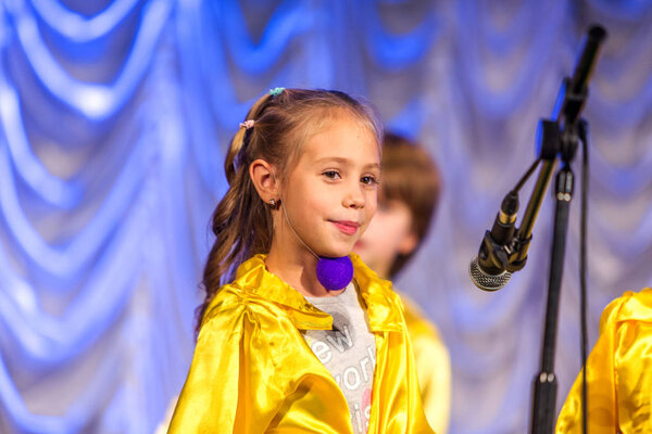 Odessa, Ukraine - December 24, 2015: Children's musical groups singing and dancing on stage in bright colorful clothes. Emotional, touching children's musical stage show.